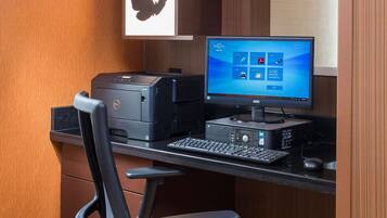A computer desk with a desktop computer, keyboard, mouse, and printer.
