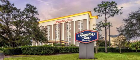 A Hampton Inn by Hilton hotel with a well-maintained lawn and a large sign in front.