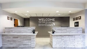 A reception area with a 'Welcome to the Sun Shine State' sign, two reception desks, and a modern interior design. - Hampton Inn Orlando-International Airport (Orlando)