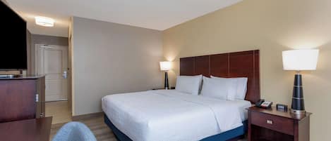 Une chambre d’hôtel avec un grand lit, des tables de chevet, un bureau et une chaise.