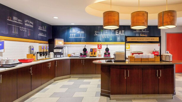 A modern kitchen with wooden cabinets, a central island, and a breakfast bar. - Hampton Inn Orlando-International Airport (Orlando)