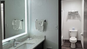 A bathroom with a marble sink, two towels hanging on hooks, a toilet, and a trash bin.