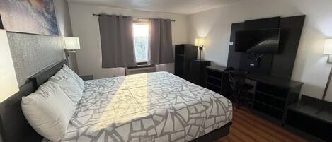 Une chambre d’hôtel avec un lit, un bureau, une télévision et une fenêtre avec des rideaux.