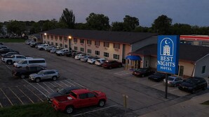 A Best Nights Hotel with a parking lot, a red pickup truck, and a building with multiple windows.