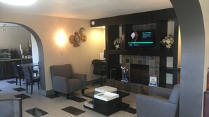 A modern living room with a fireplace, a television, and a dining area. - Days Inn by Wyndham Charlotte/Woodlawn Near Carowinds (Charlotte)