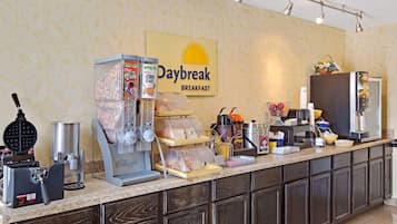 Una barra de desayuno con un letrero que dice "Daybreak Breakfast", equipada con una plancha para gofres, una máquina de café y dispensadores de cereales.