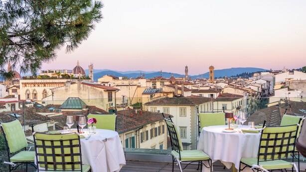 A terrace with tables and chairs overlooking a cityscape with historical buildings and a dome. - Hotel Kraft (Florence)