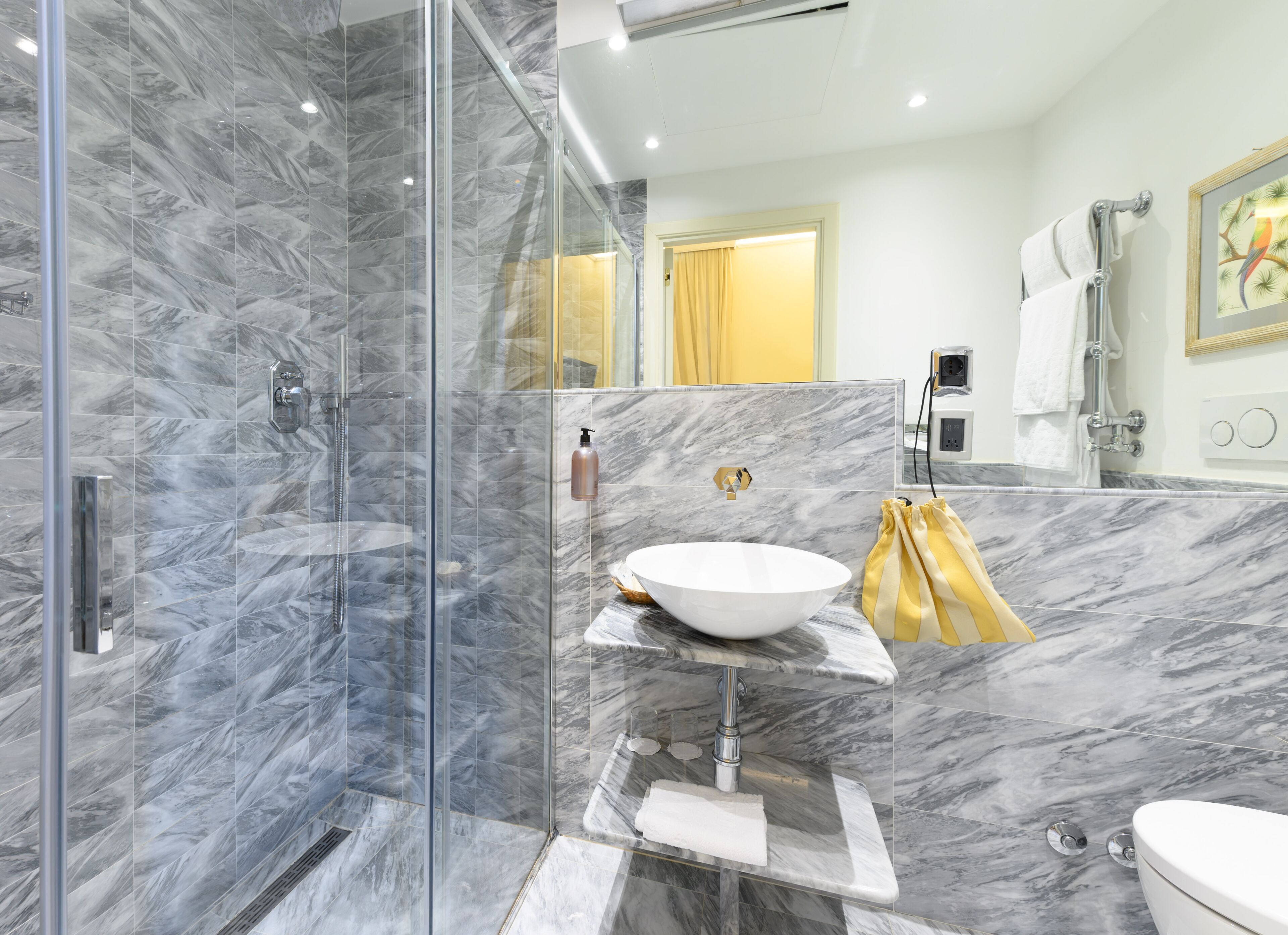 A modern bathroom with a glass-enclosed shower, a marble sink, and a toilet.