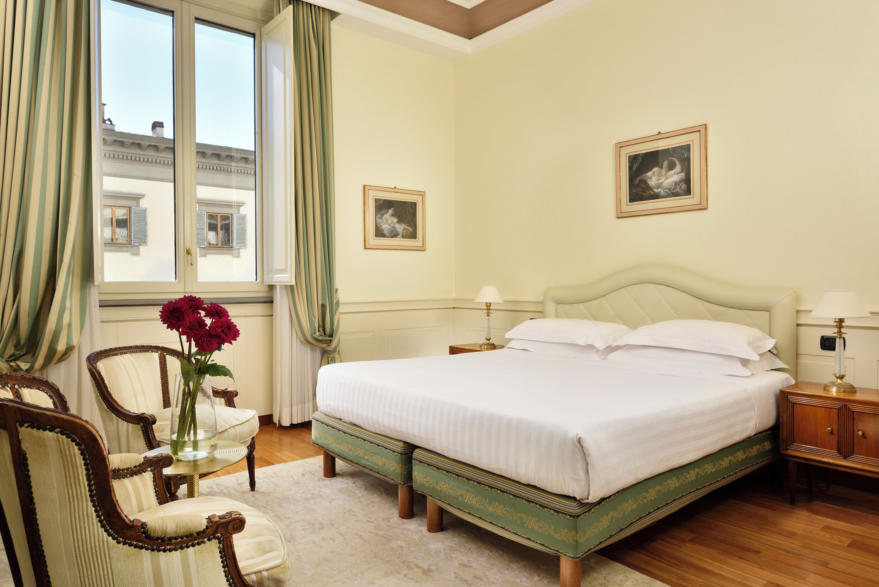 Une chambre avec un grand lit, deux tables de chevet, une chaise et une fenêtre avec des rideaux.