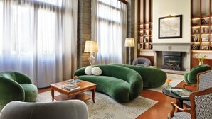 A living room with a green sofa, a fireplace, and a bookshelf. - Hotel Kraft (Florence)