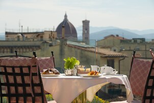 A table set for breakfast with a view of historic buildings and mountains.