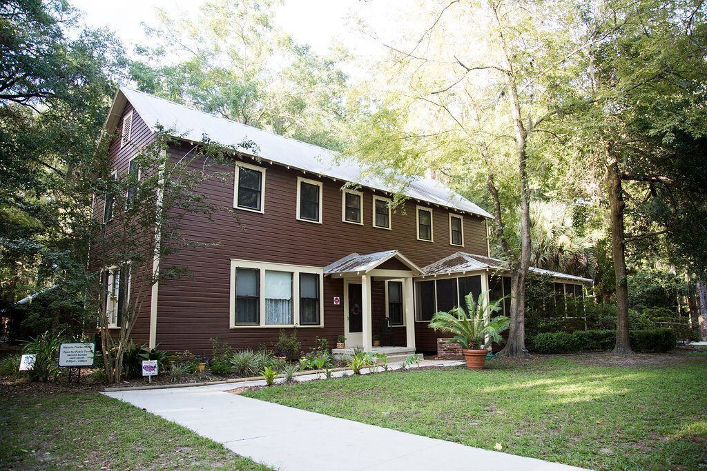A two-story house with a front porch, surrounded by a well-maintained lawn and trees.
