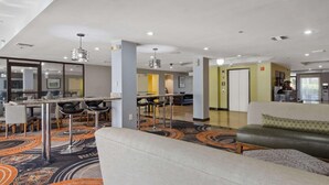 Un moderno vestíbulo de hotel con zona de bar, asientos y mostrador de recepción.