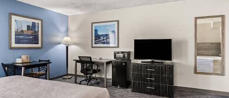 A hotel room with a bed, desk, chair, television, and a mirror.