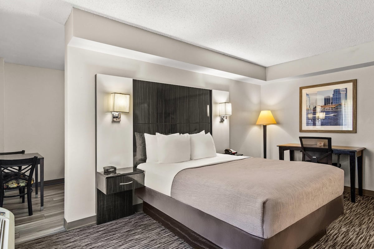 A hotel room with a large bed, bedside lamps, a desk, and a chair.