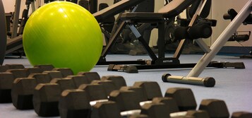 Un gimnasio con equipo de ejercicio, incluyendo mancuernas y una pesa rusa.