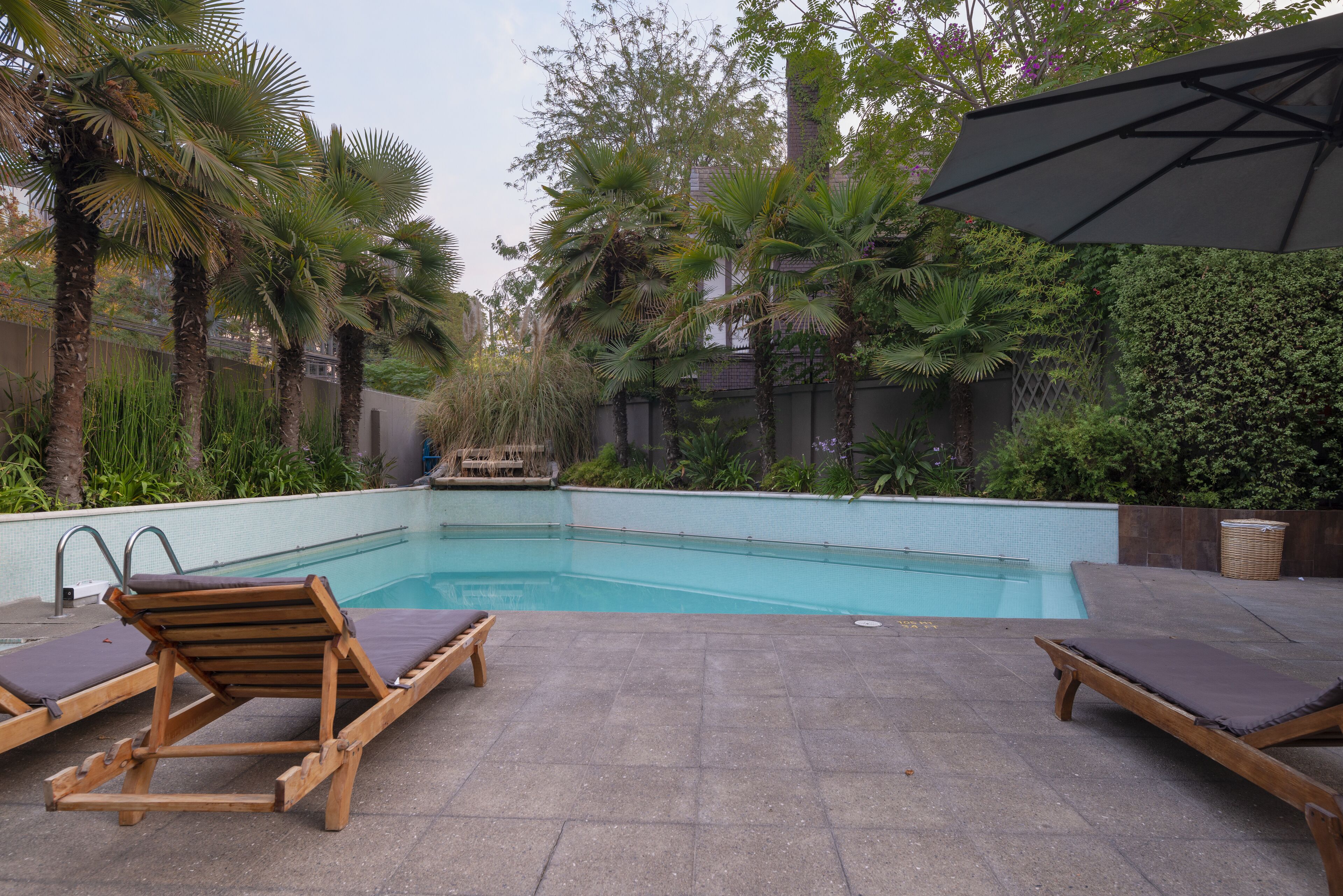 Una piscina con sillas de descanso y una pérgola.