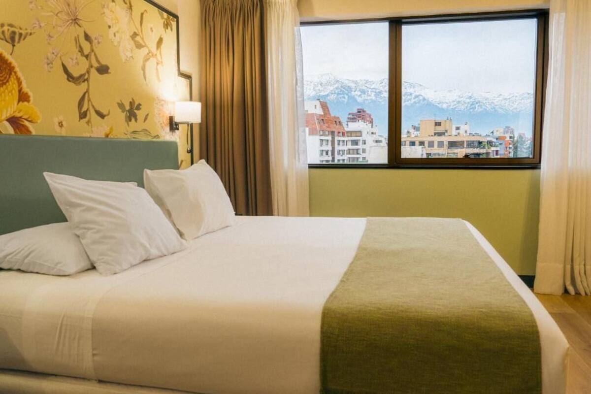 Ein Hotelzimmer mit Bett, Blick auf schneebedeckte Berge und einem Vorhangfenster.