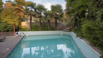 Una piscina rodeada de exuberante vegetación y palmeras.