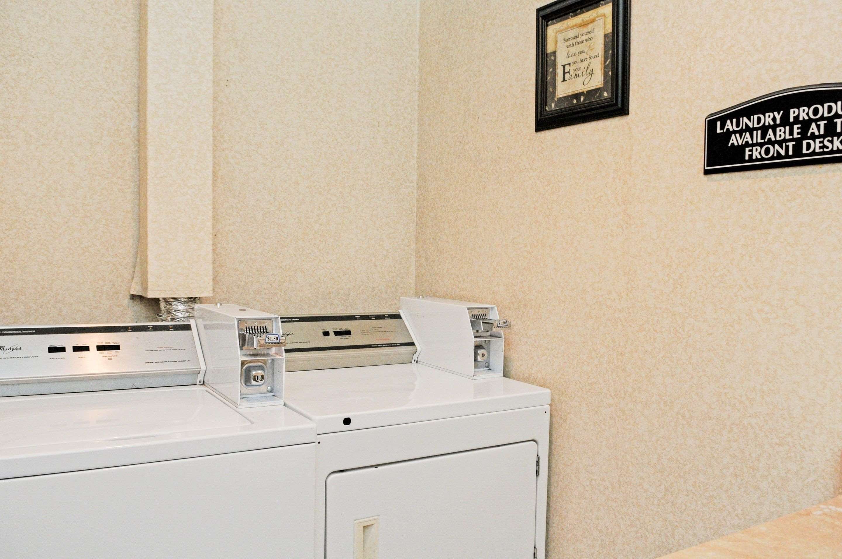 A front desk area with a washing machine and a sign indicating laundry services are available at the front desk.