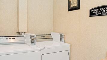A front desk area with a washing machine and a sign indicating laundry services are available at the front desk.