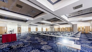 A large conference room with rows of tables and chairs, a stage with a podium, and a red tablecloth. - Arvena Kongress (Bayreuth)