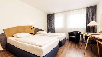 Une chambre d’hôtel avec deux lits, un bureau et une chaise.