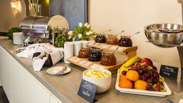 Un buffet proposant une variété d’aliments, notamment du beurre, du miel, des fruits et des confitures.