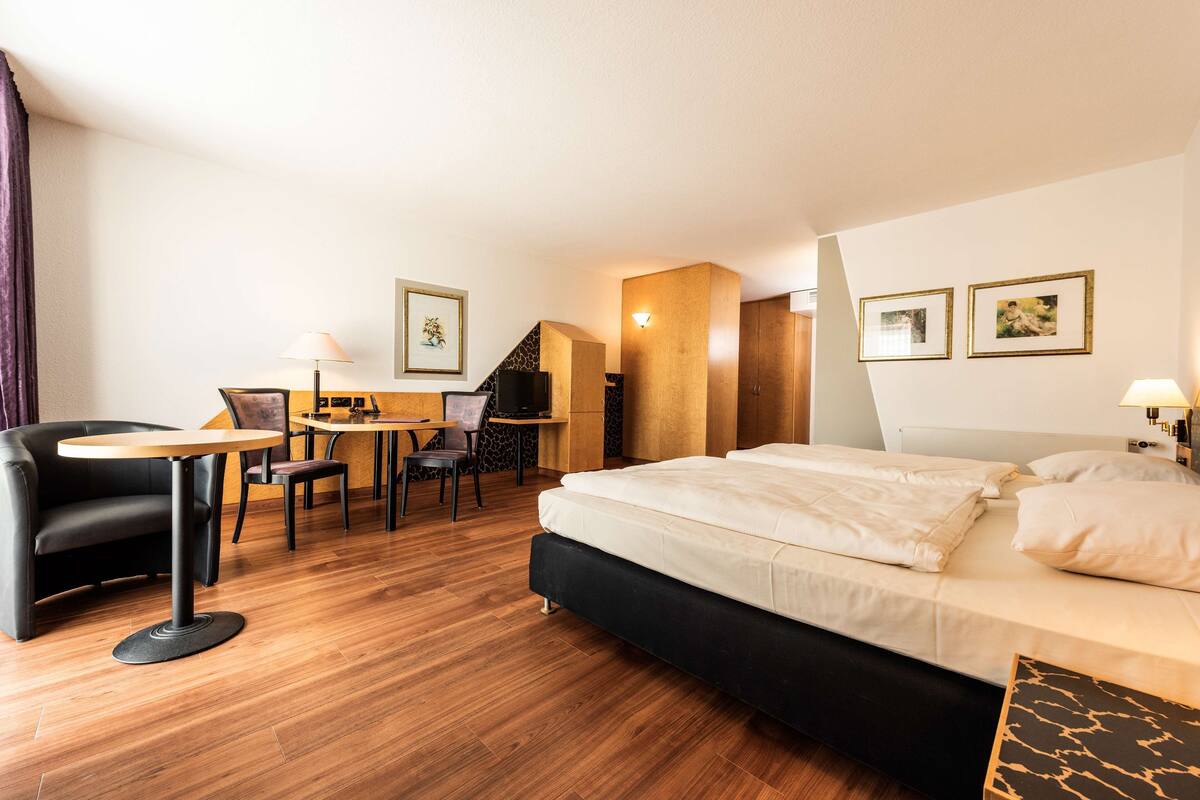 A hotel room with a bed, a desk, a chair, and a sofa.