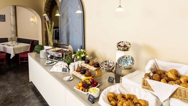 A breakfast buffet with various food items and a seating area with tables and chairs. - Arvena Kongress (Bayreuth)