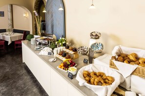 A breakfast buffet with various food items and a seating area with tables and chairs. - Arvena Kongress (Bayreuth)