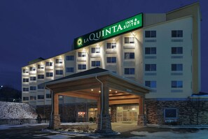 A La Quinta Inn & Suites building with a covered entrance, stone facade, and multiple windows. - La Quinta Inn & Suites by Wyndham Butte (Butte)