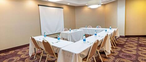 A conference room with tables set for a meeting, equipped with water bottles and nameplates.