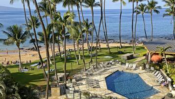 A resort with a pool, beach, and palm trees.