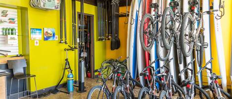 Una habitación con paredes amarillas, bicicletas y tablas de surf.