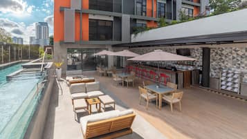 Una piscina al aire libre, sombrillas, sillones reclinables de piscina