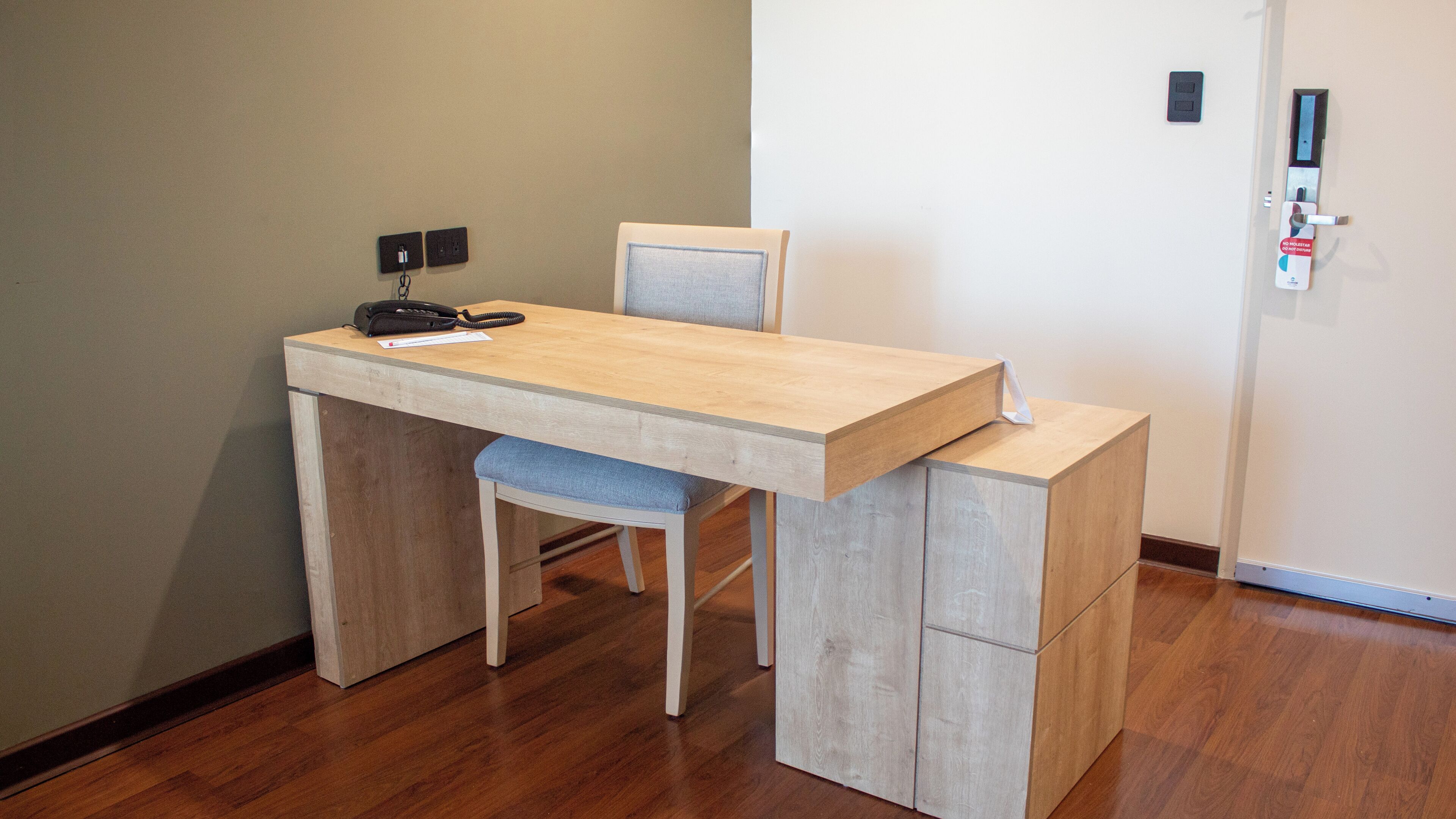 Een functionele werkruimte met bureau, stoel en een klein kastje.