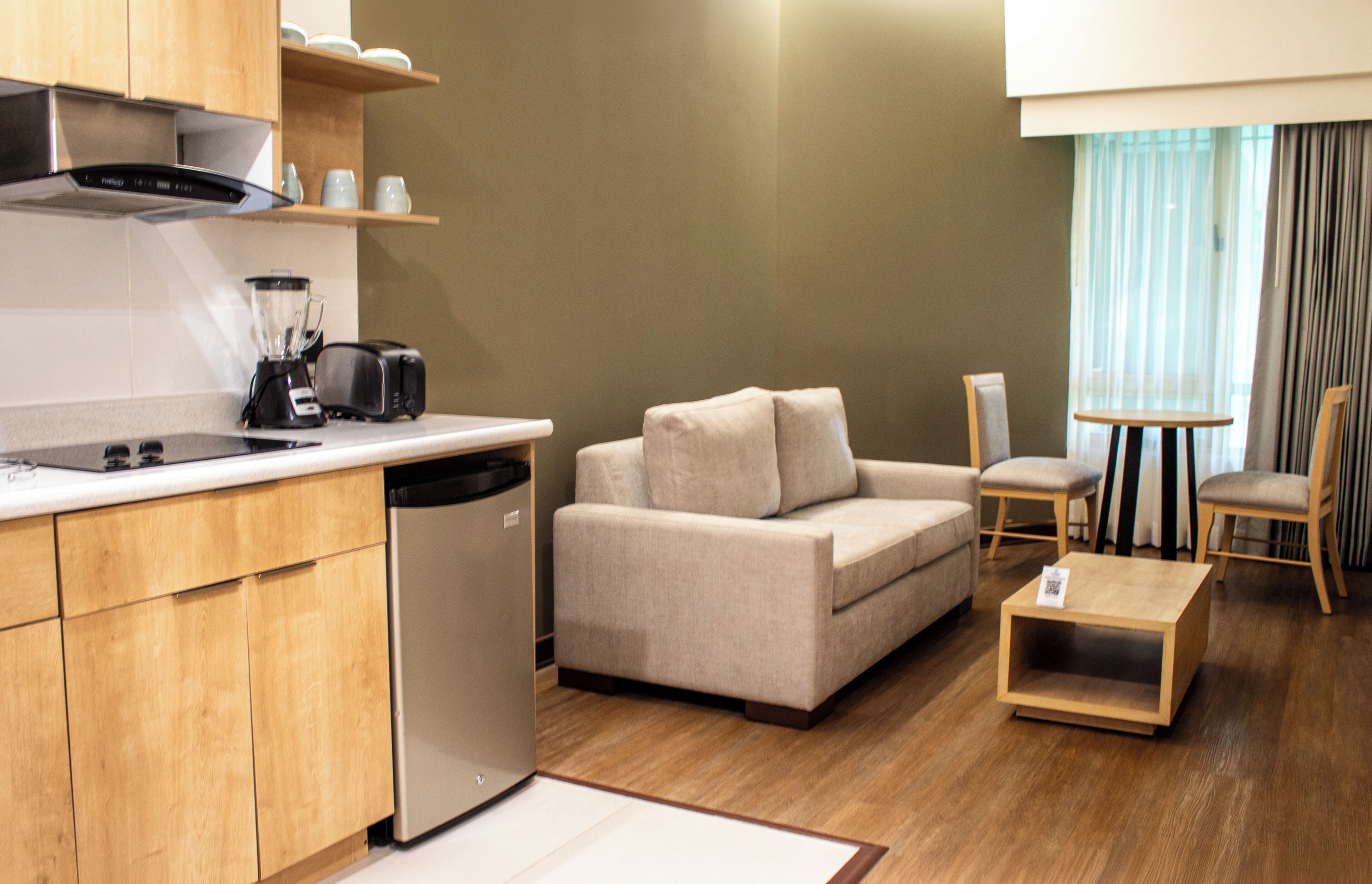 A compact living space with a kitchenette, a sofa, a dining table, and a chair.