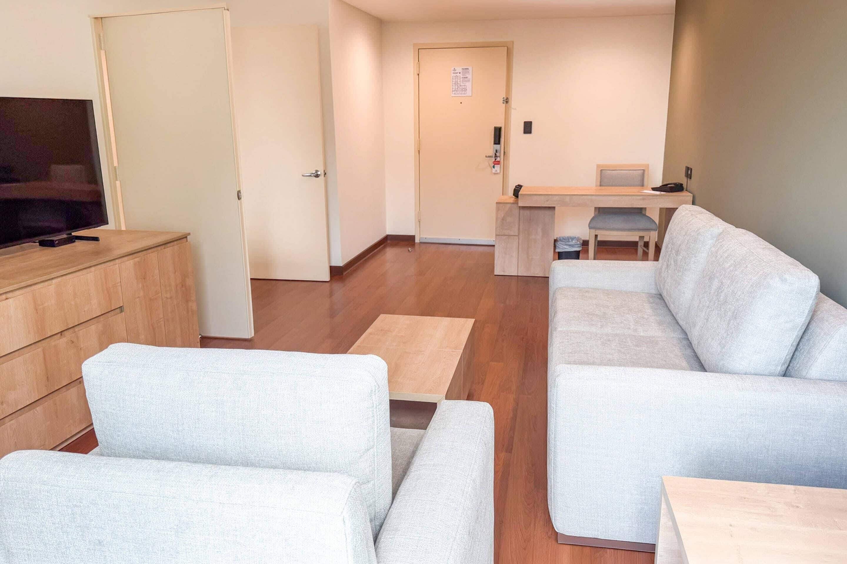 A modern living room with a sofa, a TV, a wooden cabinet, and a desk with a chair.