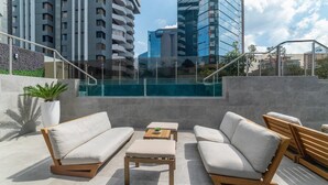 Un lounge en la azotea con asientos al aire libre y una piscina.