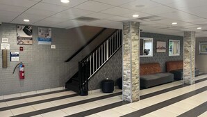 Un vestíbulo con una escalera, un extintor, una zona de recepción con un sofá y una pared con un diseño decorativo.