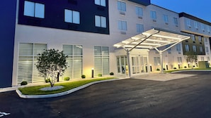 Ein modernes Hotel mit überdachter Eingangspartie, zahlreichen Fenstern und einem gepflegten Rasen.