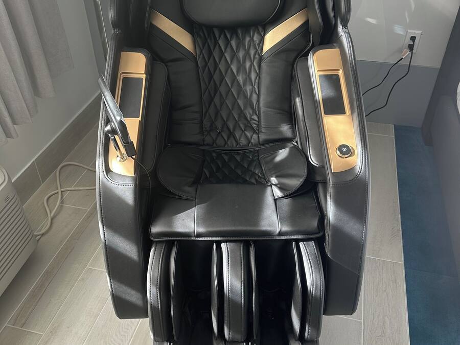 A massage chair with a control panel, a footrest, and a power cord.