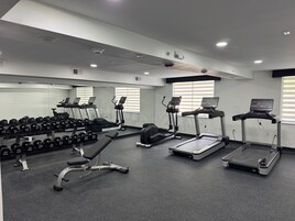 A gym with treadmills, dumbbells, and a bench.