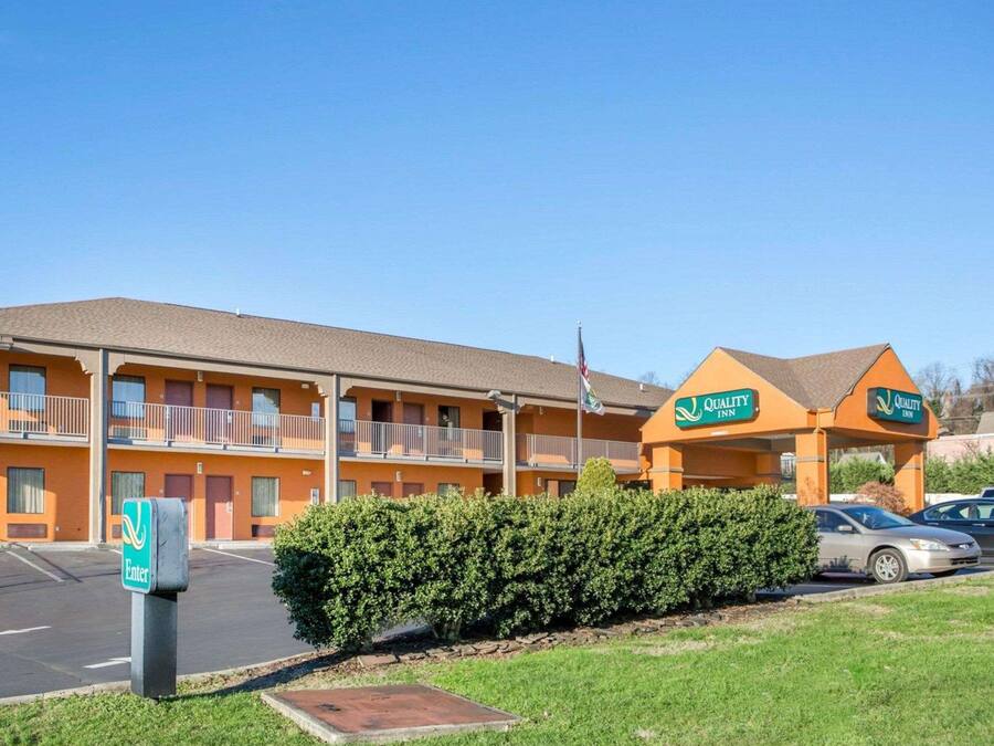 A motel with a two-story building, a covered parking area, and a well-maintained lawn.