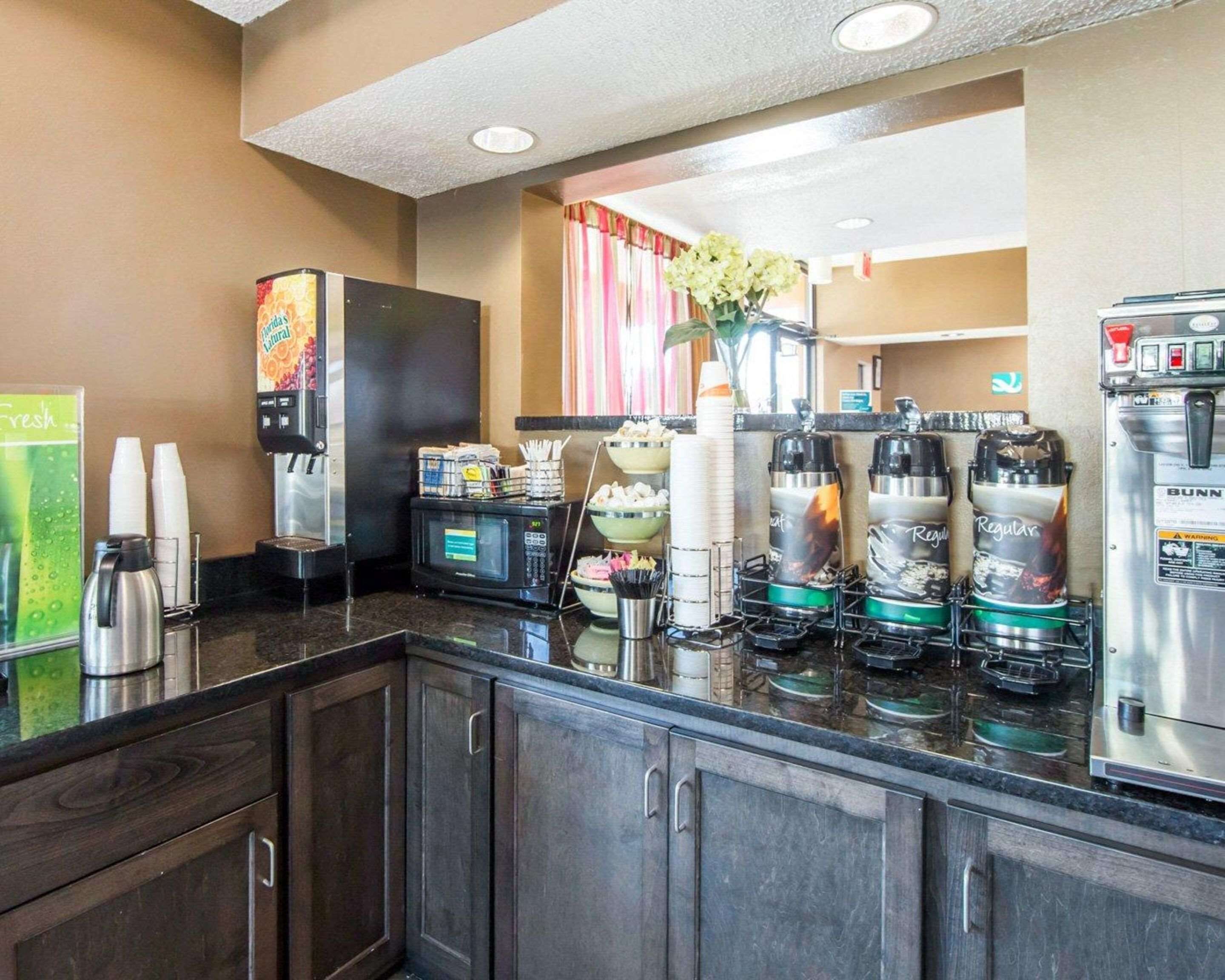 Una cocina de hotel con cafetera, microondas y dispensadores de bebidas.