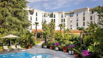 Un espace piscine comprenant des chaises longues, une piscine et un bâtiment doté de balcons et de fenêtres.