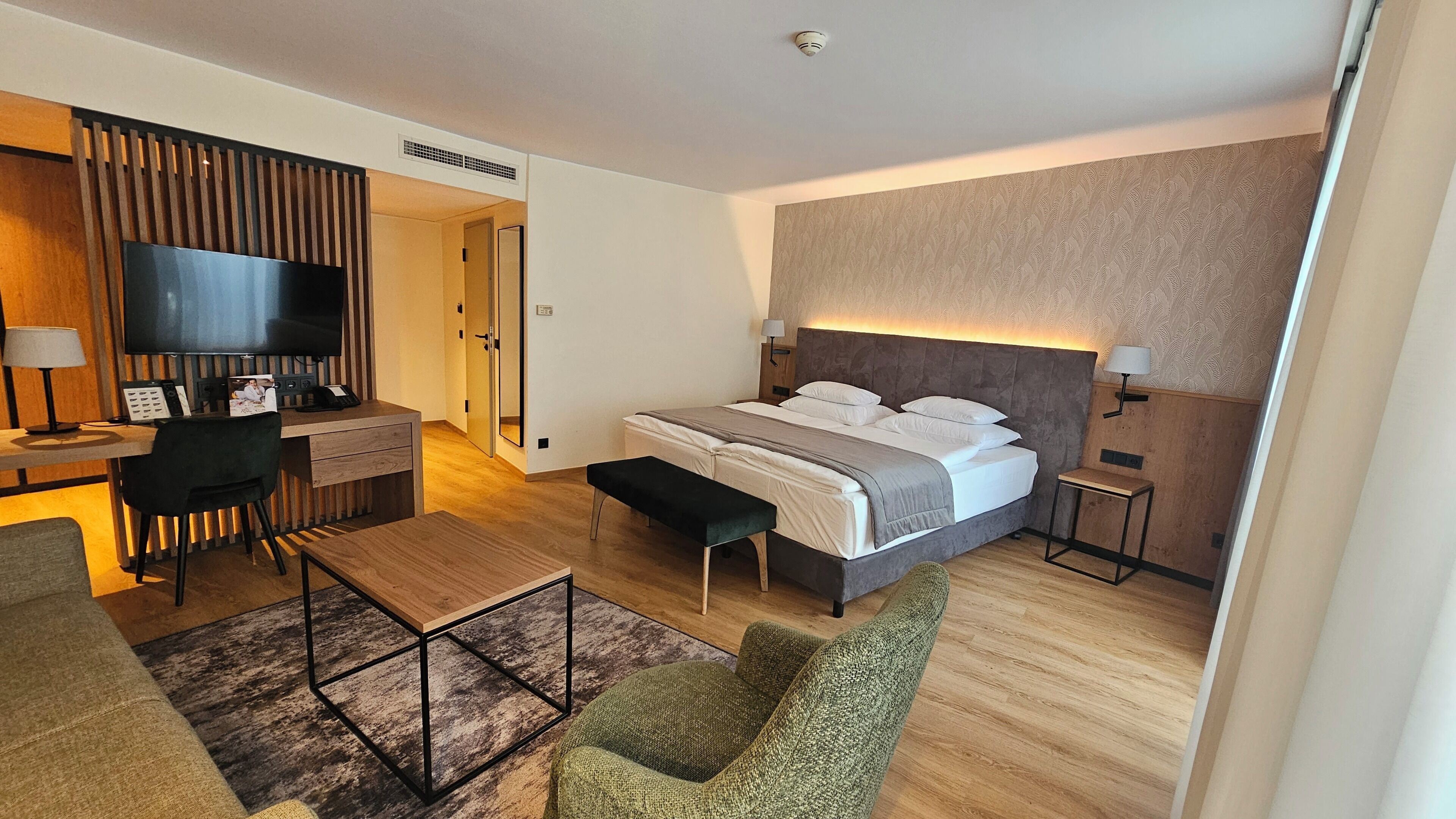 Una habitación de hotel moderna con cama, escritorio, televisión y zona de estar.