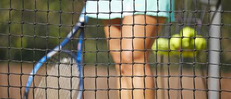 A tennis court with a net in the foreground.