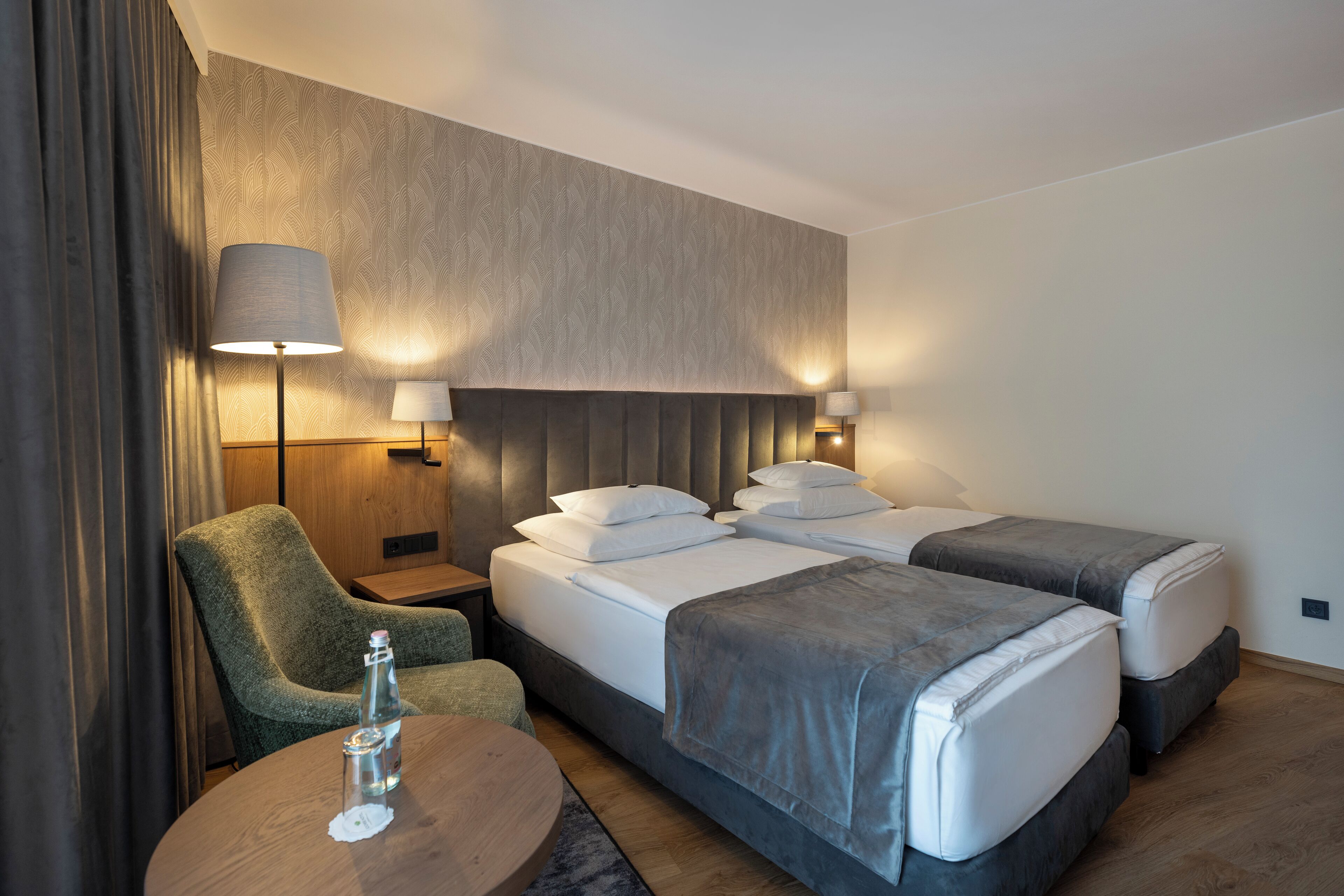 A hotel room with a bed, two bedside tables, a chair, and a round table.